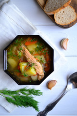 Fish soup with salmon and dill on a white table