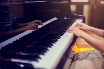 Selective focus to kid fingers and  piano key to play the piano.