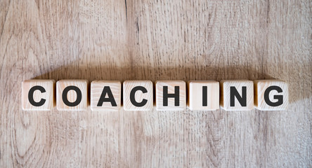 Coaching text word on wooden cubes on wooden background