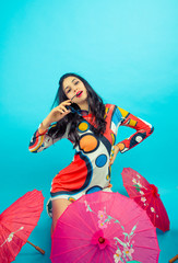  Young brunette model with dress and typical Japanese umbrellas on turquoise background