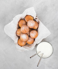 Cottage cheese balls with powdered sugar in a box and milk on a light background
