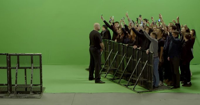 GREEN SCREEN 3/4 view huge crowd of people with phones in hands at live concert or show behind barrier. Shot on RED Helium 8K, Prores 4444