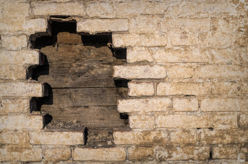Old weathered brick wall. Peeling cracked paint on red brick