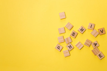 Pile of wooden letters on the surface on a yellow background, selective focus