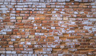 Old weathered brick wall. Peeling cracked paint on red brick