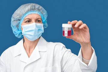 Middle aged woman doctor holding container with blood test and coronavirus vaccine