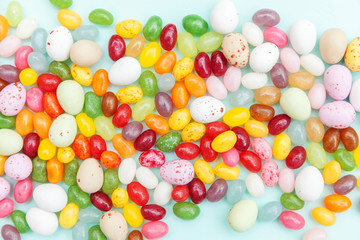 Fototapeta na wymiar Happy Easter concept. Preparation for holiday. Easter candy chocolate eggs and jellybean sweets isolated on trendy pastel blue background. Simple minimalism flat lay top view copy space.