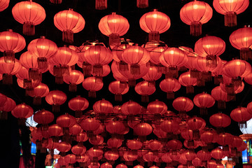 A series of red Chinese lanterns at night and illuminated arranged in a circle