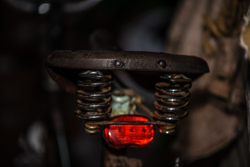 Old fashioned bicycle saddle with red back light and luxury suspension