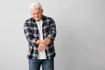 Senior man suffering from Parkinson syndrome on grey background