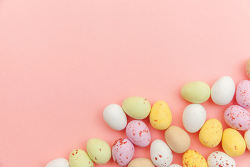 Fototapeta na wymiar Happy Easter concept. Preparation for holiday. Easter candy chocolate eggs and jellybean sweets isolated on trendy pastel pink background. Simple minimalism flat lay top view copy space.