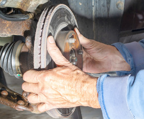 Mechanic removing worn disk rotor from front brake assembly