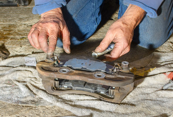 Mechanic applies grease to rear of brake pad on caliper bracket