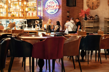 Blurred picture of interior of large beautiful restaurant with bright lighting. The waitress comes to the table and gives the visitors a menu and goes for drinks. Lifestyle. Defocused restaurant