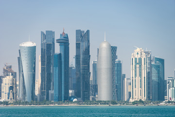 Panoramic view of modern skyline of Doha through the blue water. Concept of wealth and luxury