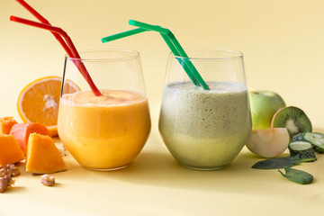 Two healthy vegetarian diet smoothies in glasses on a yellow background.