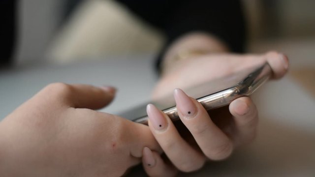 Female with pink mails hands using a smartphone