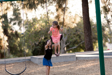 Sisters are playing and using teamwork at the playground.