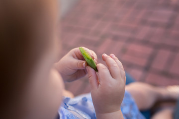 A toddler is enjoying a snack outside in the summer time.