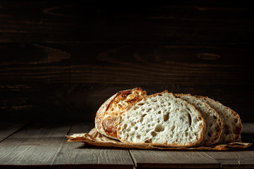 Bread, traditional sourdough bread cut into slices on a rustic wooden background. Concept of traditional leavened bread baking methods. Healthy food.