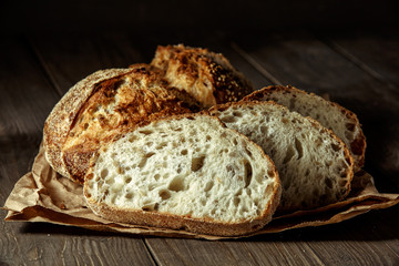 Bread, traditional sourdough bread cut into slices on a rustic wooden background. Concept of...