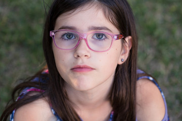 Close up of a young girl wearing glasses in the summertime.