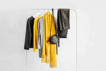 Female clothes in yellow and blue color on hanger on white background.  Jumper, shirt, jeans and scarf. Spring/autumn outfit. Minimal concept.