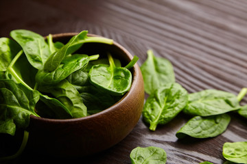 Spinach fresh green leaves in a bowl on wooden background