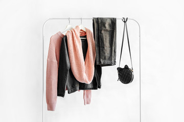 Female clothes in pastel pink and gray color on hanger on white background.  Jumper, shirt, jeans...