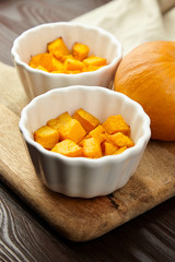 Baked pumpkin in white ceramic bowl on wooden background
