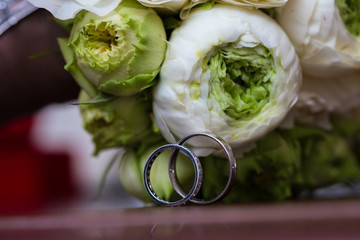 Bouquet of white roses and silver wedding rings.
