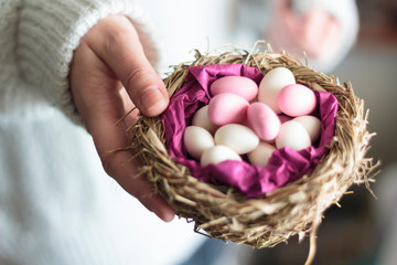 Woman hands holding bird nest with Easter eggs