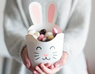 Woman hands holding rabbit box with sweet easter almonds inside