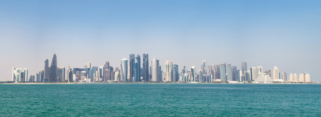 Naklejka premium Panoramiczny widok na nowoczesną panoramę Doha przez błękitną wodę. Pojęcie bogactwa i luksusu