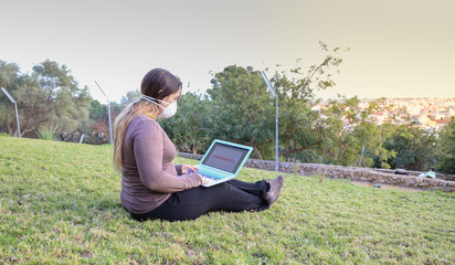 Young girl wearing protective mask using laptop.