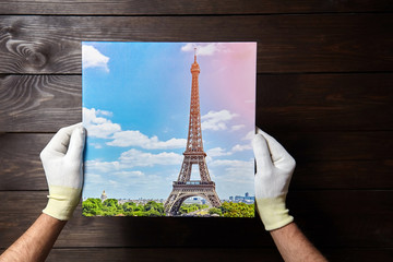 Person holding photo printed on canvas on wooden background