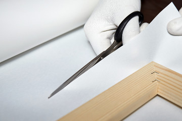 Person cutting canvas with scissors, canvas wrapping