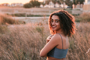 Smiling young black curly haired girl walking on the beach