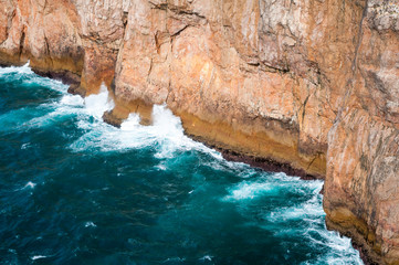 Turbulent blue-green seas crashing in white waves against the dramatic rock cliffs of Cape Saint...