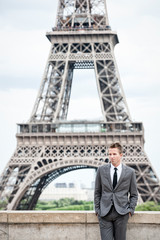 Serious European businessman standing alone in front of the Eiffel Tower in Paris,  France