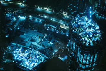 Modern construction site of high rise building in Dubai at night, view from above.