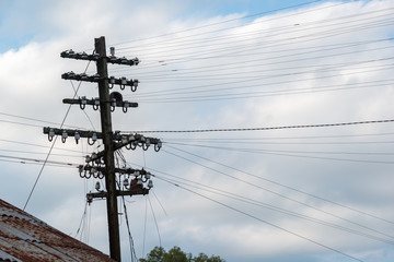 Bunch of electricity cables wires on a wooden post with some bird nests on a cloudy day