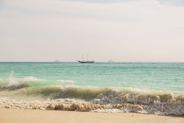 Amazing beauty  Atlantic ocean turquoise water surface. Boat merging with blue sky and white clouds. Aruba island. Unforgettable view. 