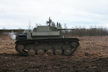 Ggreen tank of the second world war rides on a field with dry grass on Festival of living history