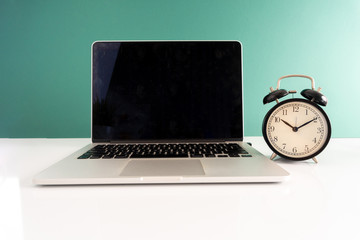 Laptop and clock with punctuality concept.