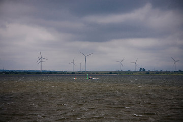  summer landscape with a cloudy sky and a wind farm on the horizon at Puck Bay in Poland