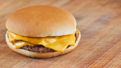 thin cheeseburger or hamburger on a wooden board with diagonal lines background.selective focus. copy space.  wide crop.