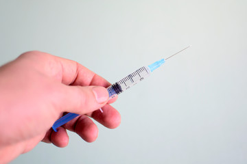 Injection syringe in hand on light background