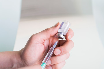Hand holding syringe and medicine vial prepare for injection in operating room  background. Copy space