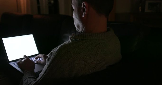 Man Working on Laptop in dark in the evening at home